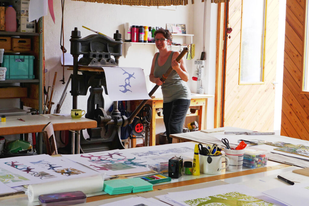 HeaderarbeiteninderEifel Anna Eiber beim Drucken an der kleinen Kniehebelpresse